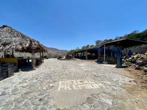 Outdoor distillery with wide stone walkway and Mezcal Premium written in white tiles.